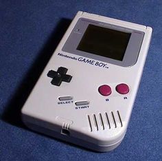 an old nintendo game boy sitting on a blue surface