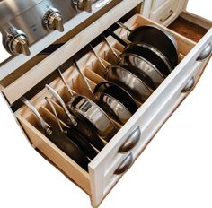 an open drawer with pots and pans in it