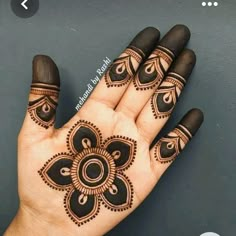 a hand with henna tattoos on it and an intricate flower design in the middle