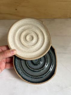 a hand is holding two black and white bowls