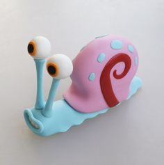 a close up of a toy snail on a white surface with blue and pink colors