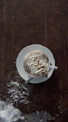 a cup of hot chocolate and whipped cream on a saucer covered in powdered sugar