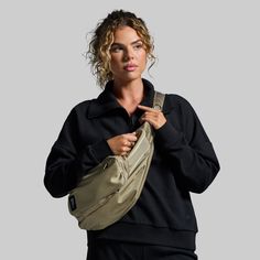 a woman is holding her purse and posing for the camera while wearing a black top