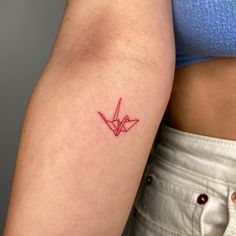 a woman's arm with a red origami tattoo on the left side