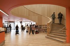 people are walking up and down the stairs in an open area with bookshelves