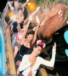 several girls are riding on a roller coaster at the amusement park, with their arms in the air