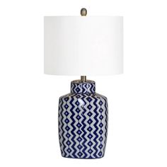 a blue and white table lamp with a white shade on the top, sitting against a white background