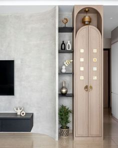 a living room with a large wooden cabinet in the center and a flat screen tv on the wall