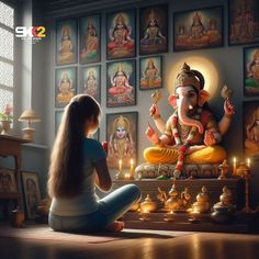 a woman sitting on the floor next to an elephant statue with candles in front of it