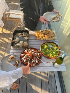 a person holding a plate with food on it near other plates and bowls full of food