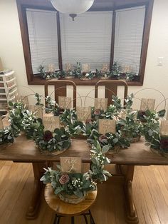 the table is set with place cards and greenery for guests to sit down at