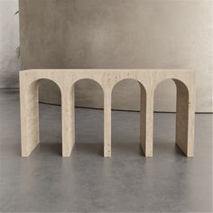 a bench made out of plywood with arches on the top and bottom, sitting in front of a concrete wall