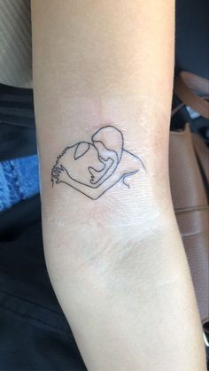 a small tattoo on the arm of a woman's left arm, with a couple hugging