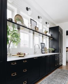 a kitchen with black cabinets and gold pulls on the countertops, along with a rug