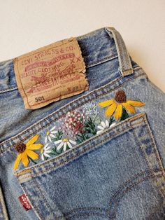 the back pocket of a pair of jeans with embroidered flowers