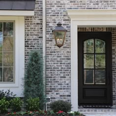 a black front door with two windows and a light hanging from it's side