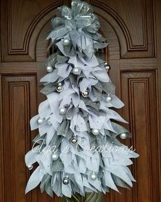 a christmas tree made out of silver and white ribbons on a door with ornaments hanging from it