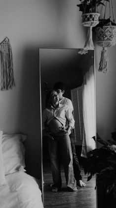 a man and woman standing in front of a mirror with their arms around each other