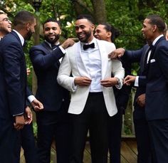 a group of men in tuxedos standing next to each other with one man wearing a bow tie