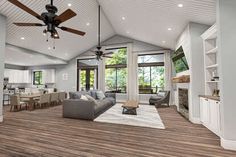 a large open concept living room with wood flooring and ceiling fan in the center