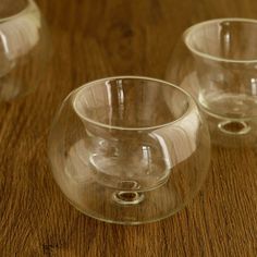 three clear glass bowls sitting on top of a wooden table