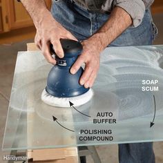 a man sanding glass table with a polisher and soap scum on it