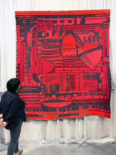 a person standing in front of a large red and black piece of art on display