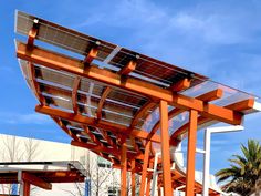 an orange wooden structure with solar panels on it's sides and palm trees in the background