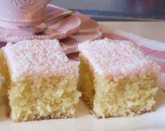 two pieces of cake on a plate with a cup and saucer in the background