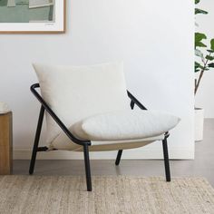 a white chair sitting on top of a rug next to a potted plant