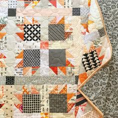 an orange and black patchwork quilt is on display