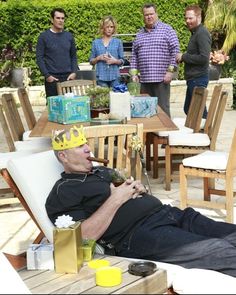 a man laying on top of a white chair next to a table filled with food