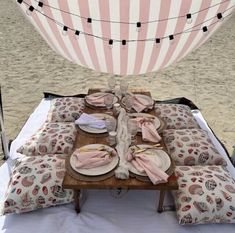 a picnic table set up on the beach with plates and napkins laid out in front of it