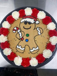 a decorated gingerbread cookie with white frosting and red roses around the edges on a black platter