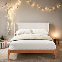 a white bed sitting in a bedroom next to a wall with christmas lights on it