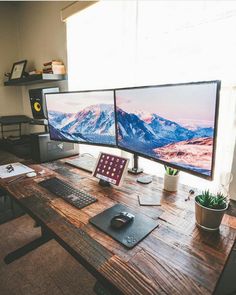 two computer monitors sitting on top of a wooden desk