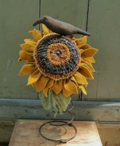 a crocheted sunflower with a bird sitting on it's back end