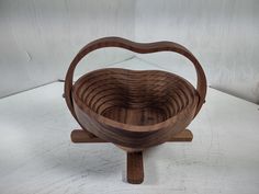 a wooden bowl sitting on top of a table next to a white wall and floor