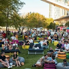 many people are sitting and standing around in the grass