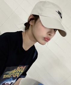 a young woman wearing a hat standing in front of a white tiled wall and toilet