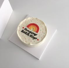 a birthday cake with the words happy birth day on it sitting on top of a piece of paper