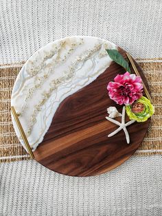 a wooden platter with flowers and shells on it