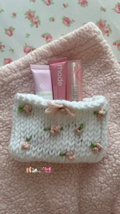 the contents of a crocheted pouch are displayed on a pink and white blanket