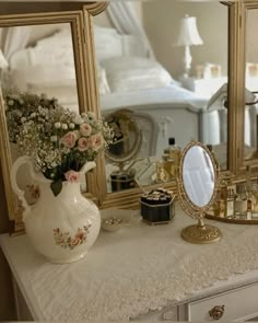 a white dresser topped with a mirror and vase filled with flowers