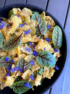 a bowl filled with cornflakes and blue flowers on top of a wooden table