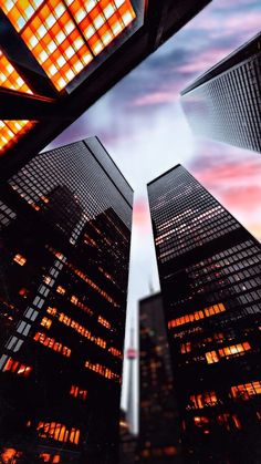 looking up at skyscrapers from the ground in front of a colorful sky line with clouds