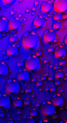 purple and red drops of water on a blue surface with light reflecting off the top