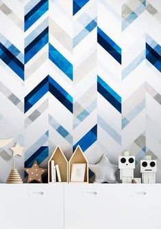 a white dresser topped with drawers under a blue and white wallpaper covered in geometric shapes