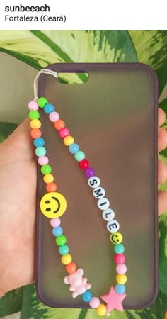 someone is holding up their phone case with beaded beads and smiley faces on it