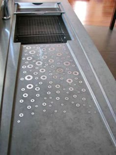 a stainless steel counter top with holes and circles on the side, in a kitchen